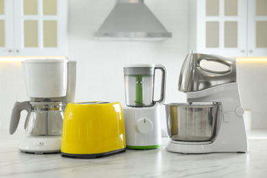 Set of modern home appliances on white marble table in kitchen