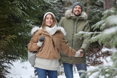 Photo of Couple in conifer forest on snowy day. Winter vacation