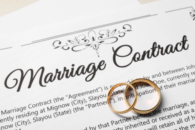 Marriage contract and gold rings on table, above view