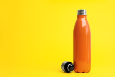 Photo of Stylish thermo bottle on yellow background, space for text