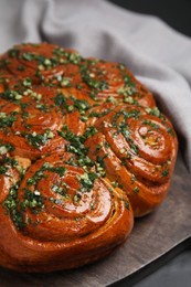 Photo of Traditional Ukrainian garlic bread with herbs (Pampushky) on black table, closeup