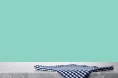 Image of Folded kitchen towel on grey table against mint background. Space for design