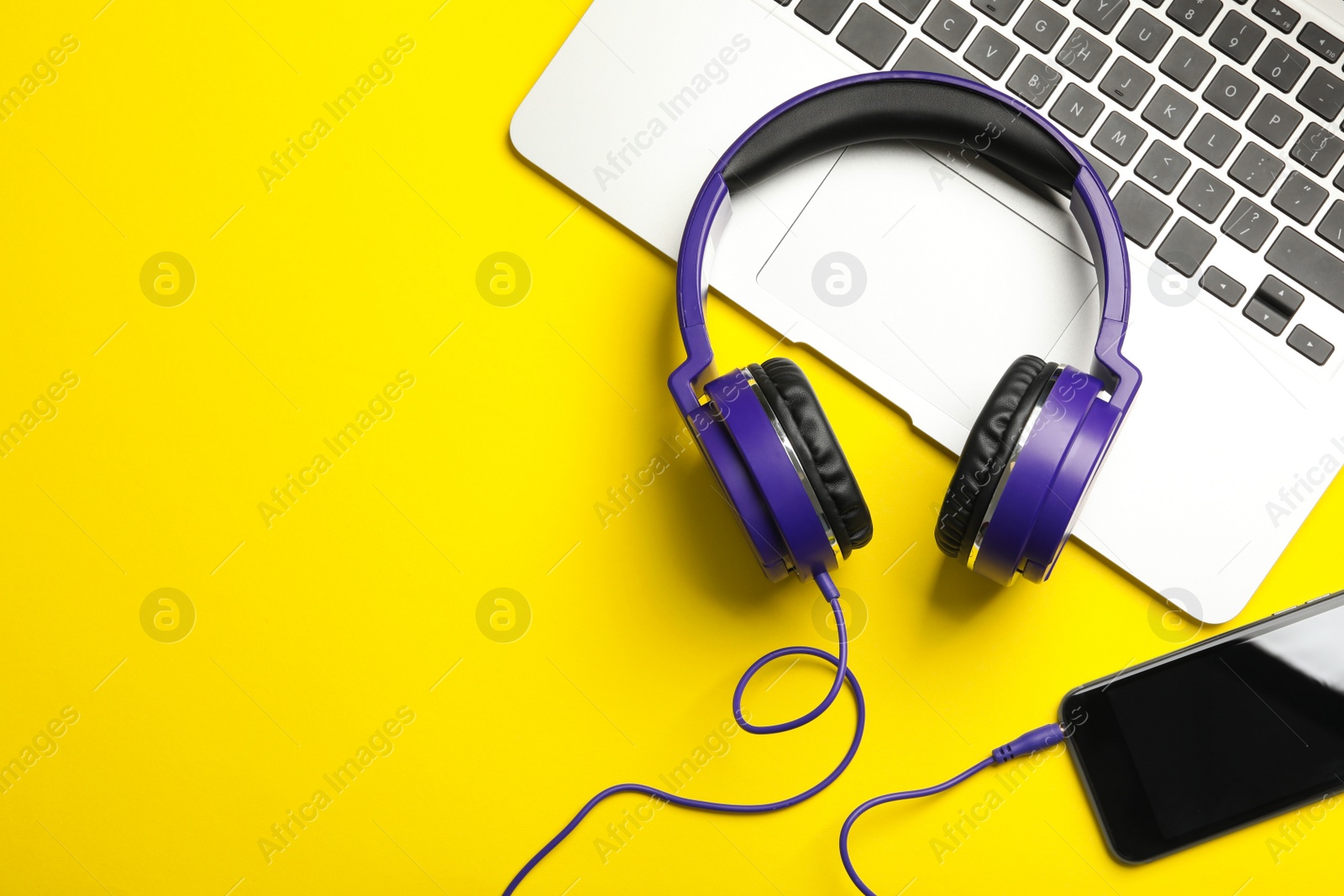 Photo of Modern headphones, phone and laptop on color background, flat lay. Space for text