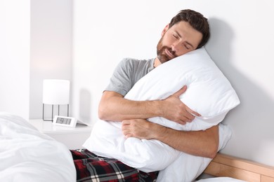 Man hugging pillow on bed at home