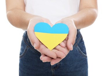 Woman holding paper heart in colors of Ukrainian flag on white background, closeup