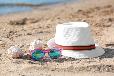 Photo of Hat, sunglasses and shells on sand near sea. Beach object