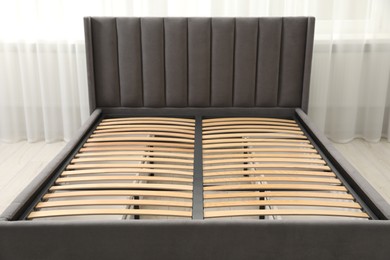 Photo of Modern bed with storage space for bedding under slatted base in room, closeup