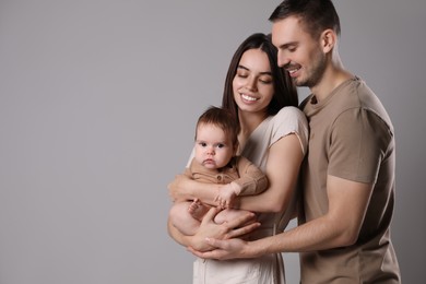 Happy family. Couple with their cute baby on grey background, space for text