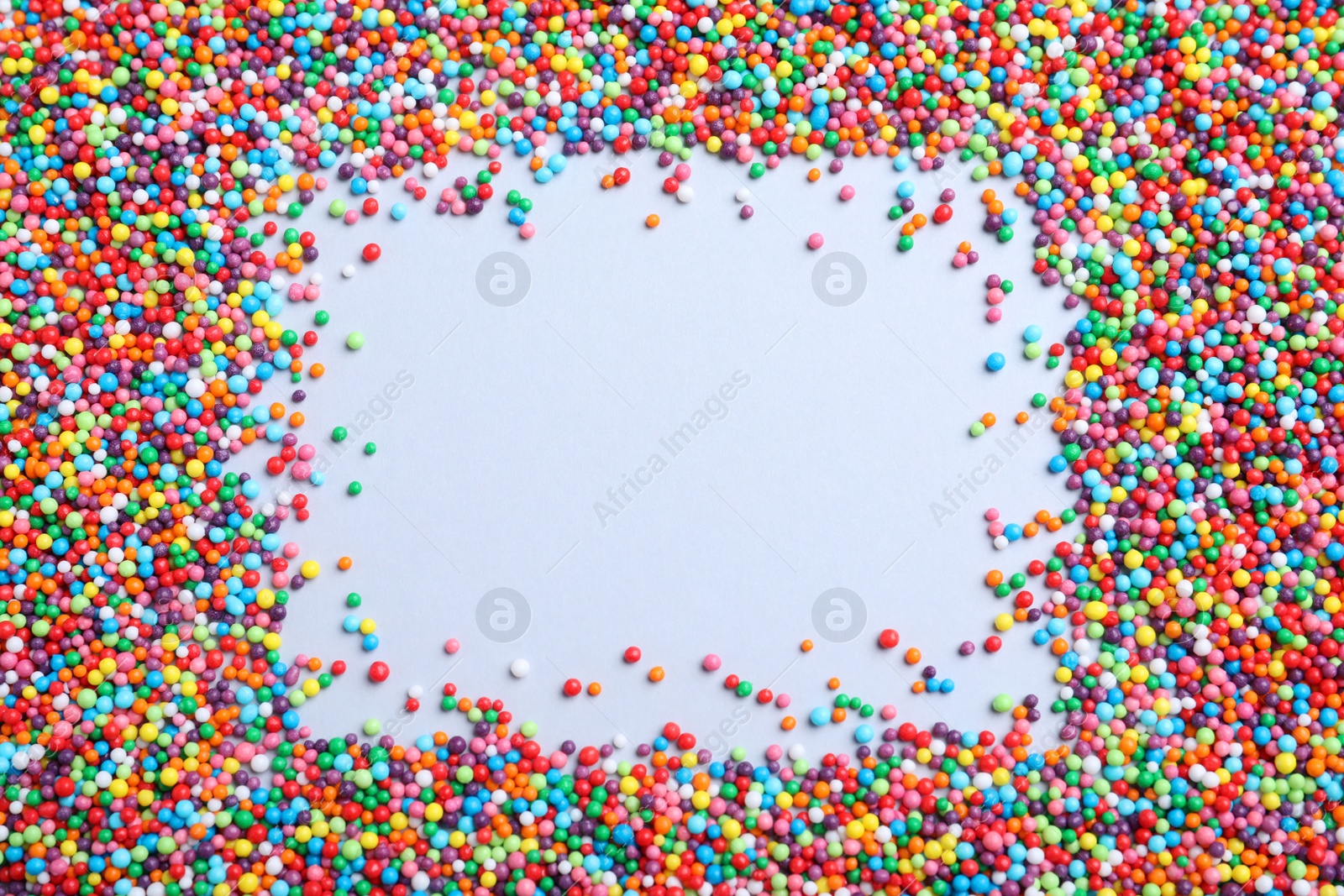 Photo of Frame of colorful sprinkles on light grey background, flat lay with space for text. Confectionery decor