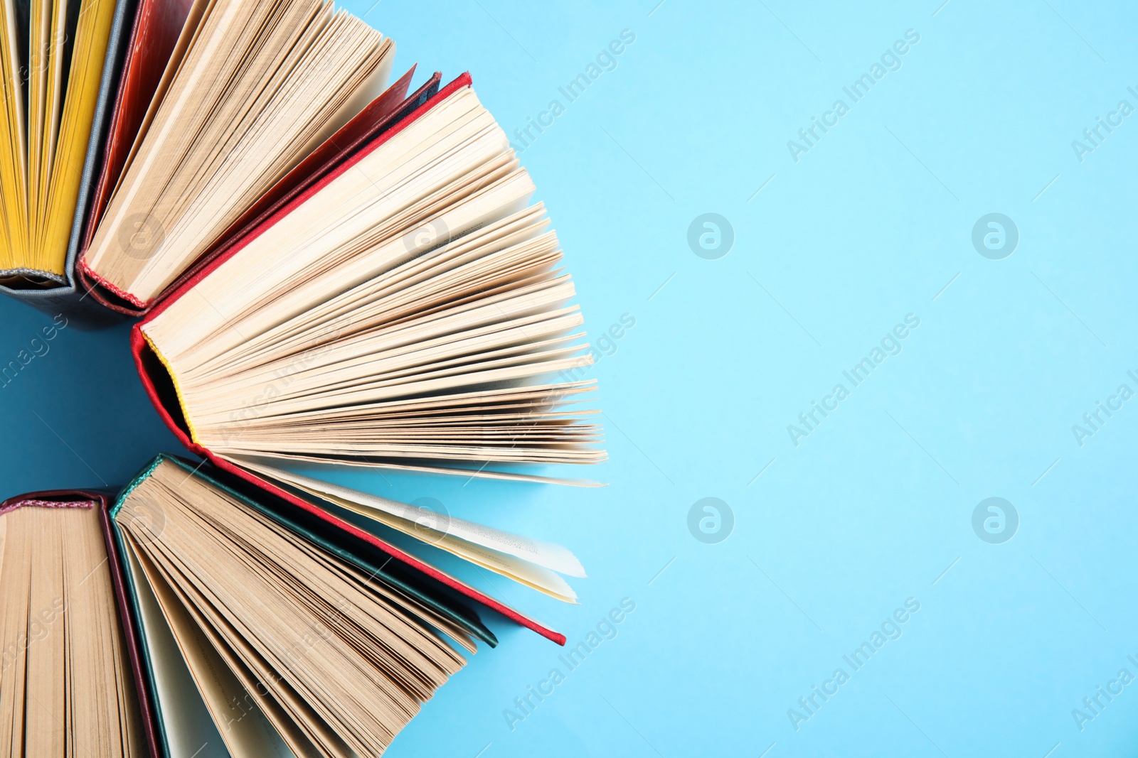 Photo of Hardcover books on light blue background, flat lay. Space for text