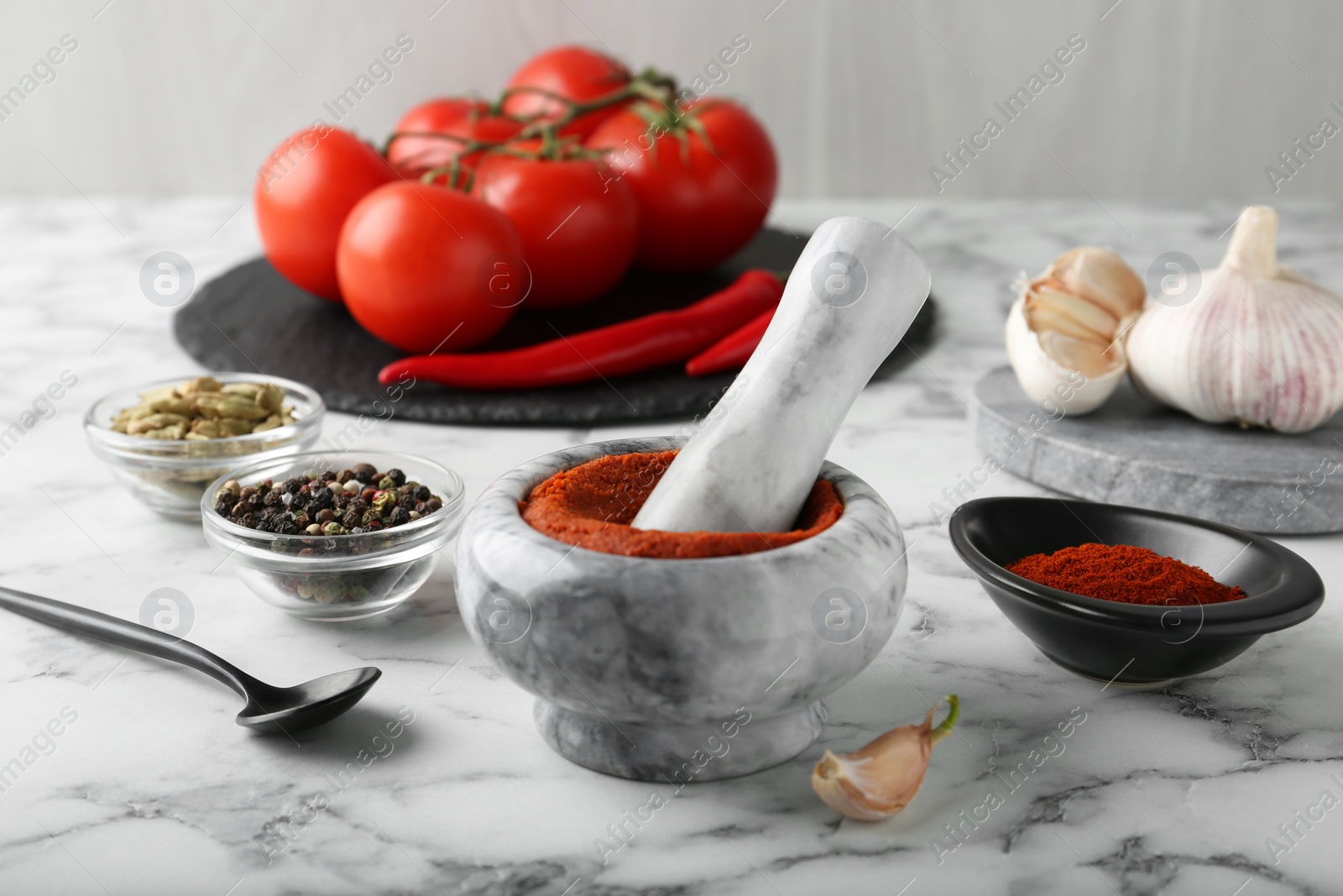 Photo of Mortar with red curry paste and ingredients on white marble table