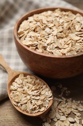 Photo of Bowl and spoon with oatmeal on wooden table, closeup