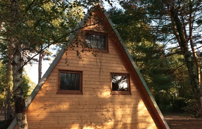 Picturesque view of modern wooden house near forest on sunny day