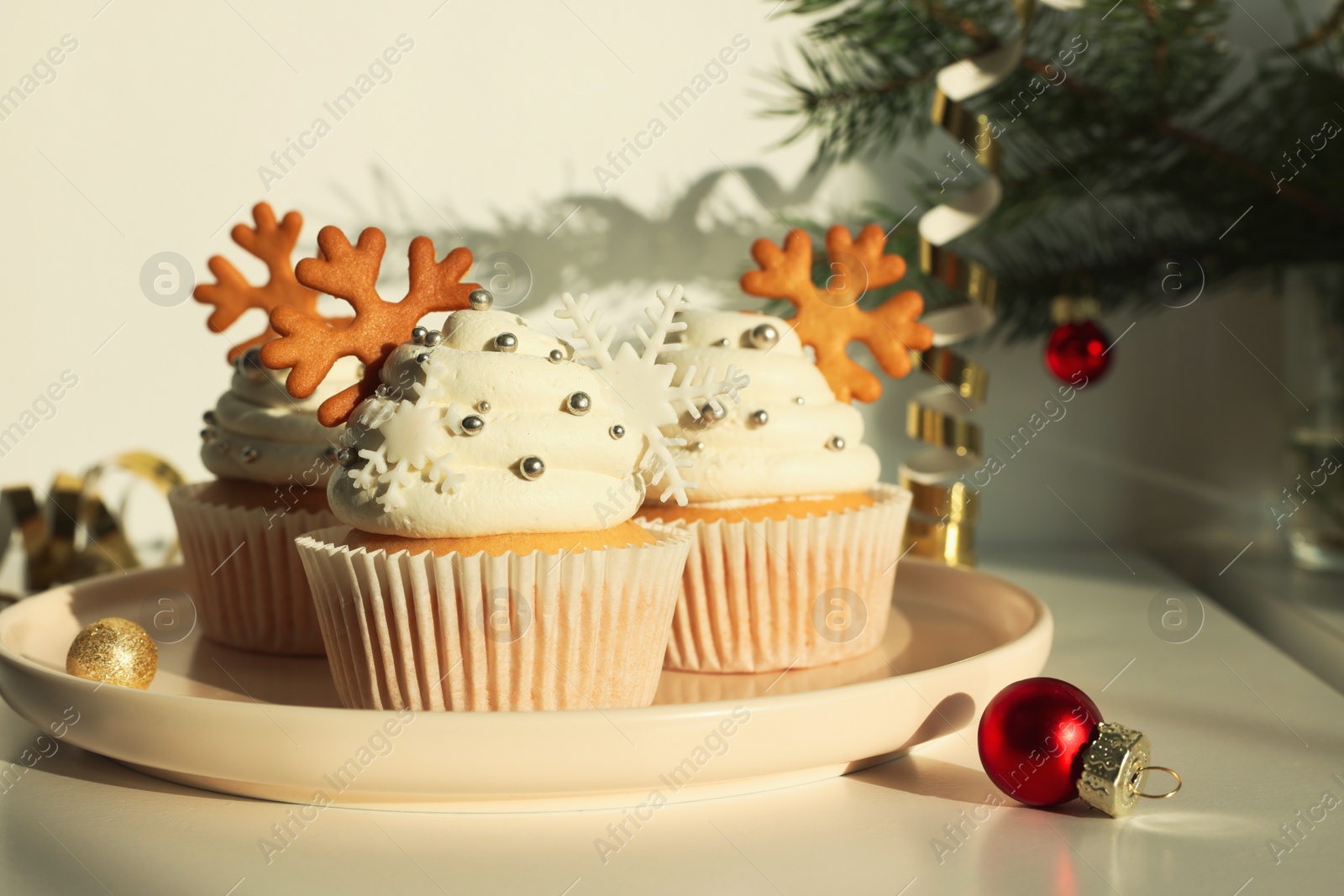 Photo of Tasty Christmas cupcakes with cream and snowflake cookies on white table