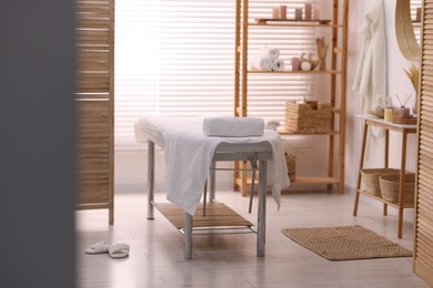 Comfortable massage table with clean towels in spa center