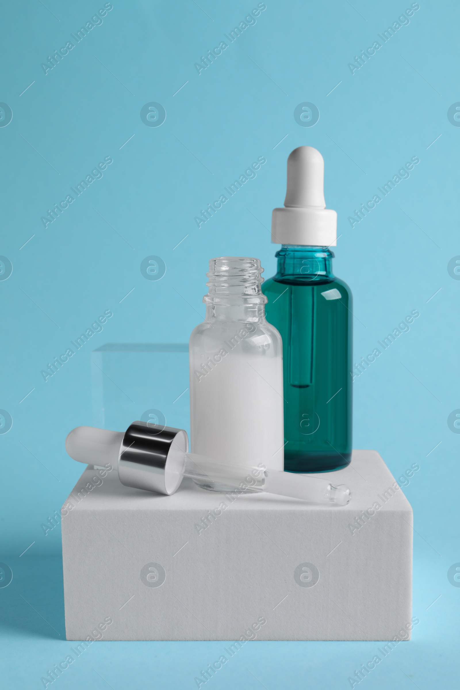 Photo of Stylish presentation of cosmetic serum on light blue background