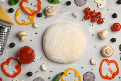Photo of Flat lay composition with dough and fresh ingredients for pizza on grey marble table