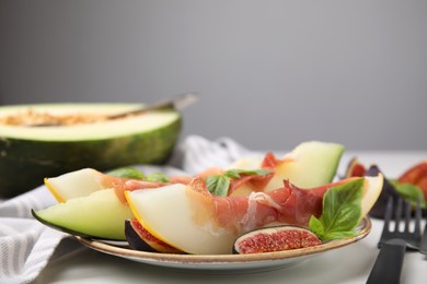 Tasty melon, jamon and figs served on white table