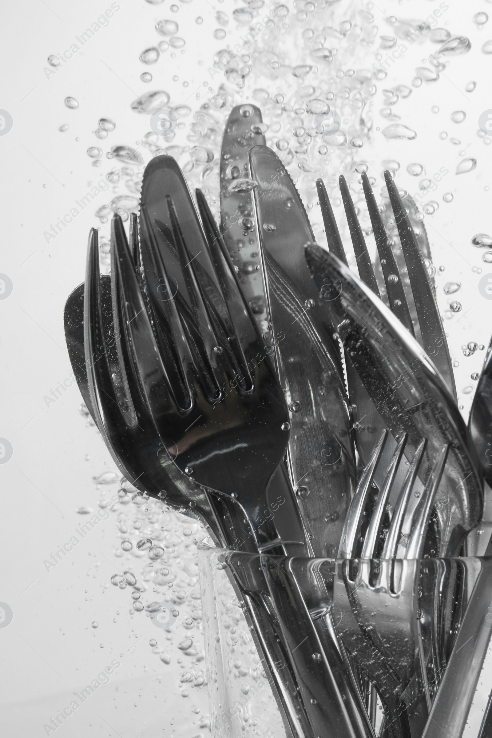 Photo of Washing silver cutlery in water on white background