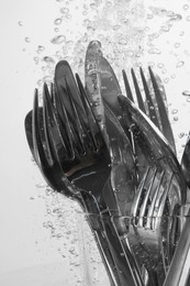 Washing silver cutlery in water on white background