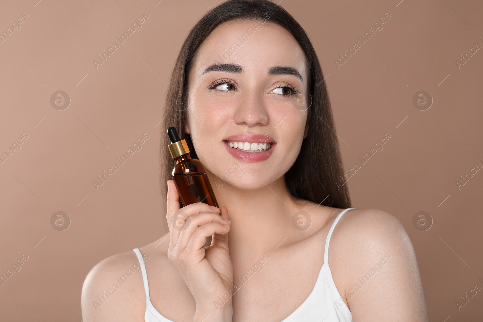 Photo of Beautiful young woman with bottle of essential oil on brown background