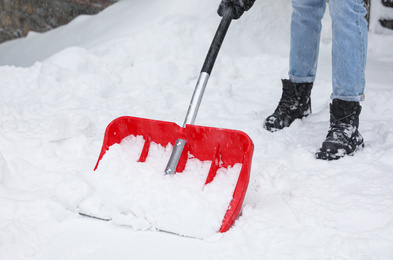 Photo of Man cleaning snow with shovel outdoors, closeup