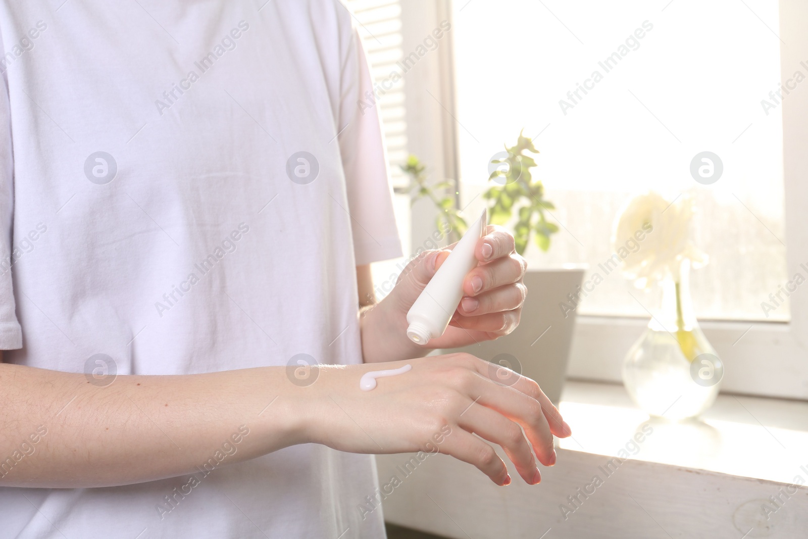 Photo of Woman applying hand cream at home, closeup