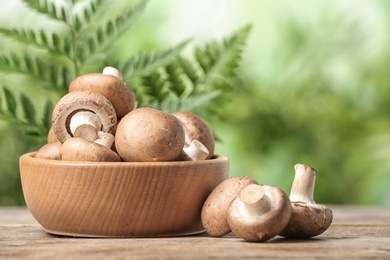 Fresh champignon mushrooms and bowl on wooden table