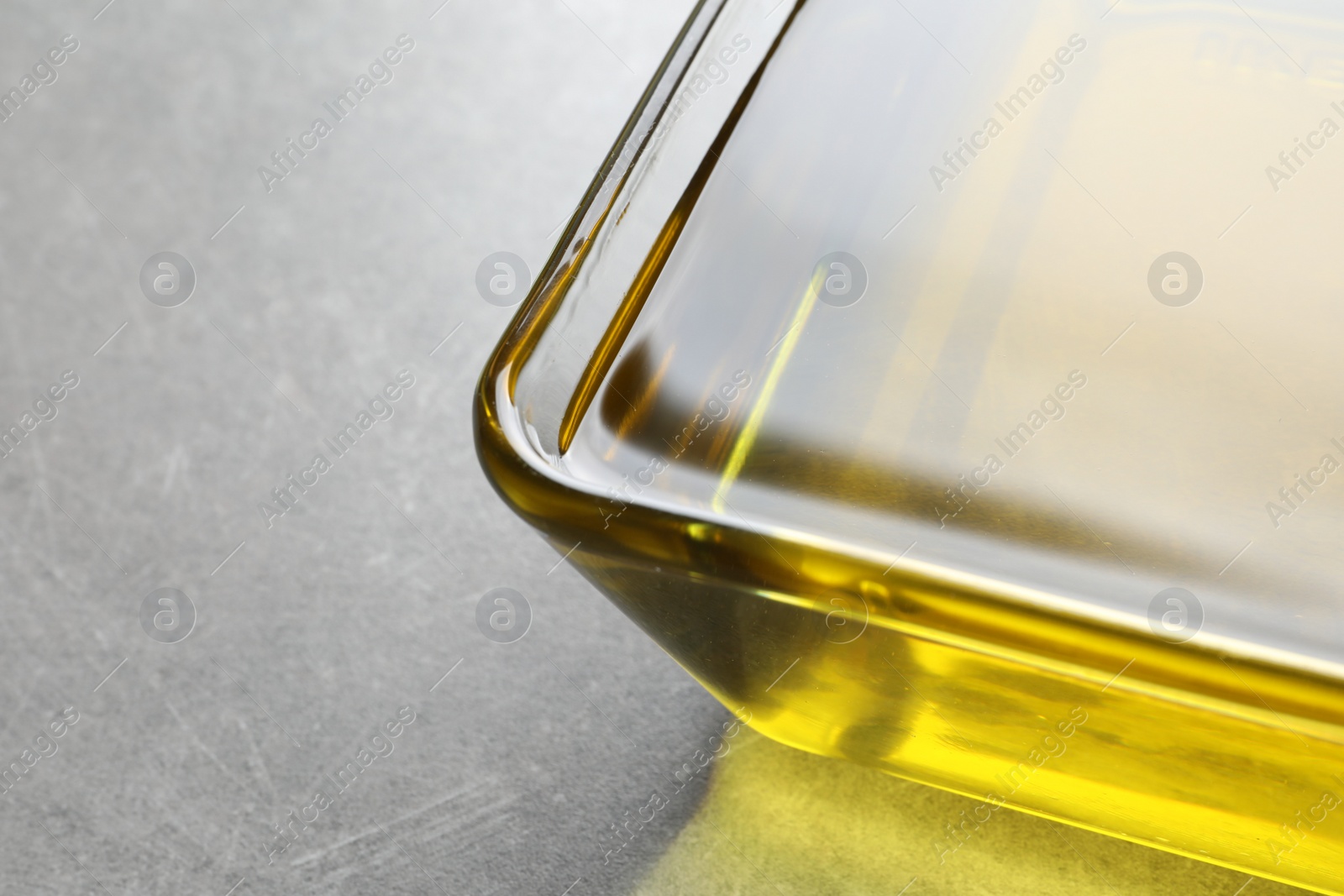 Photo of Bowl with fresh olive oil on grey background, closeup