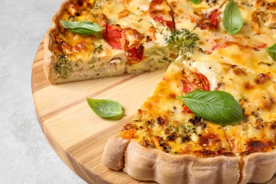 Tasty quiche with tomatoes, basil and cheese on light textured table, closeup