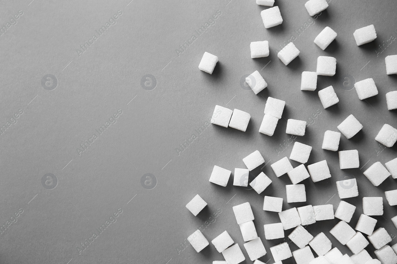 Photo of Refined sugar cubes on grey background, top view