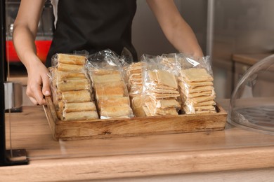 Worker holding tray with delicious pastries at desk, closeup