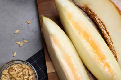 Slices of delicious honey melon on grey table, flat lay