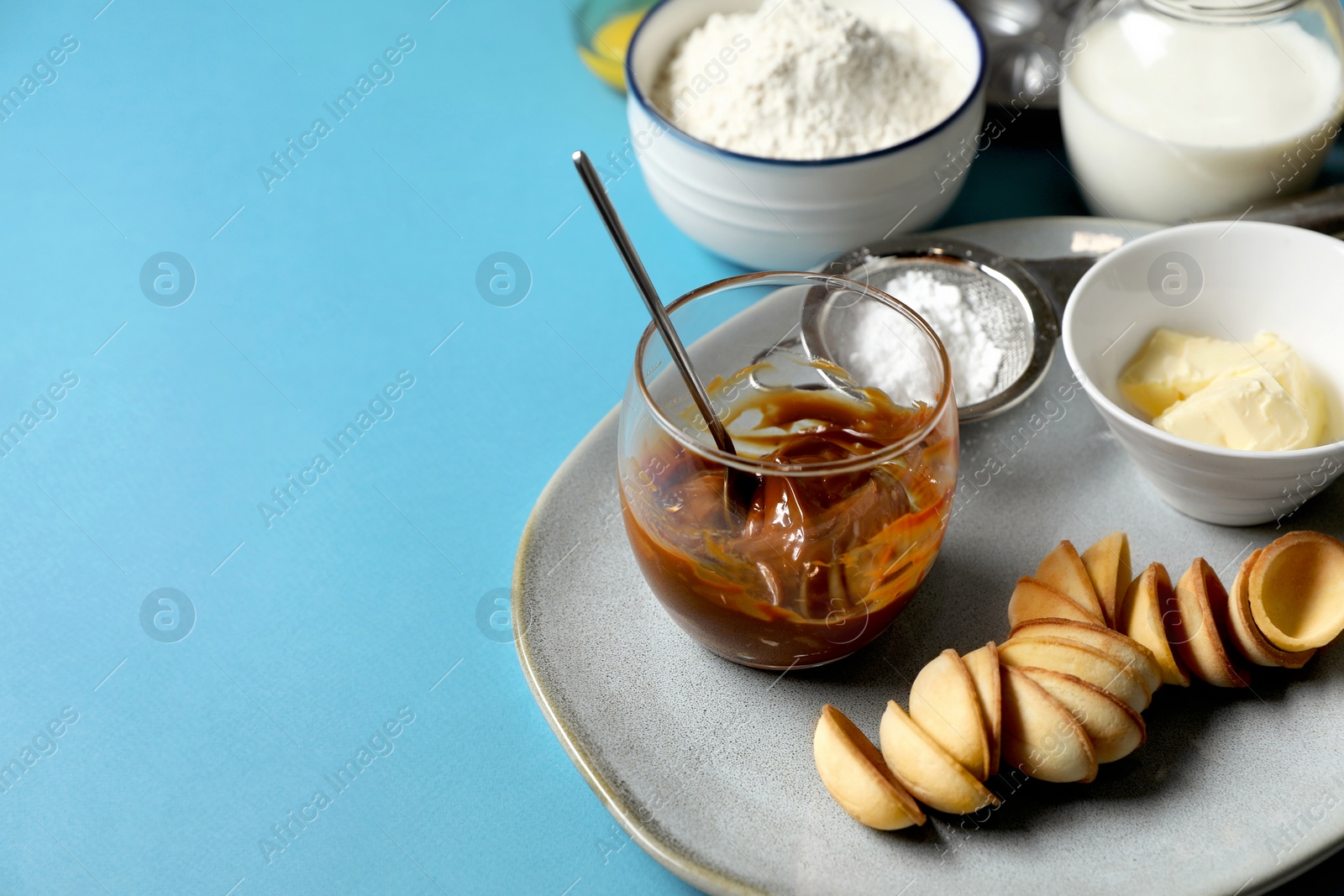 Photo of Ingredients for walnut shaped cookies on light blue table. Space for text