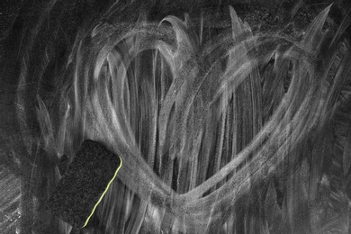 Heart on dirty chalkboard surface, closeup. School equipment