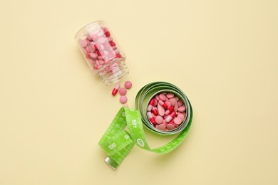 Photo of Jar of weight loss pills and measuring tape on beige background, flat lay