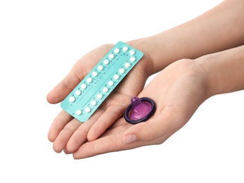 Young woman holding birth control pills and condom on white background, closeup. Safe sex concept