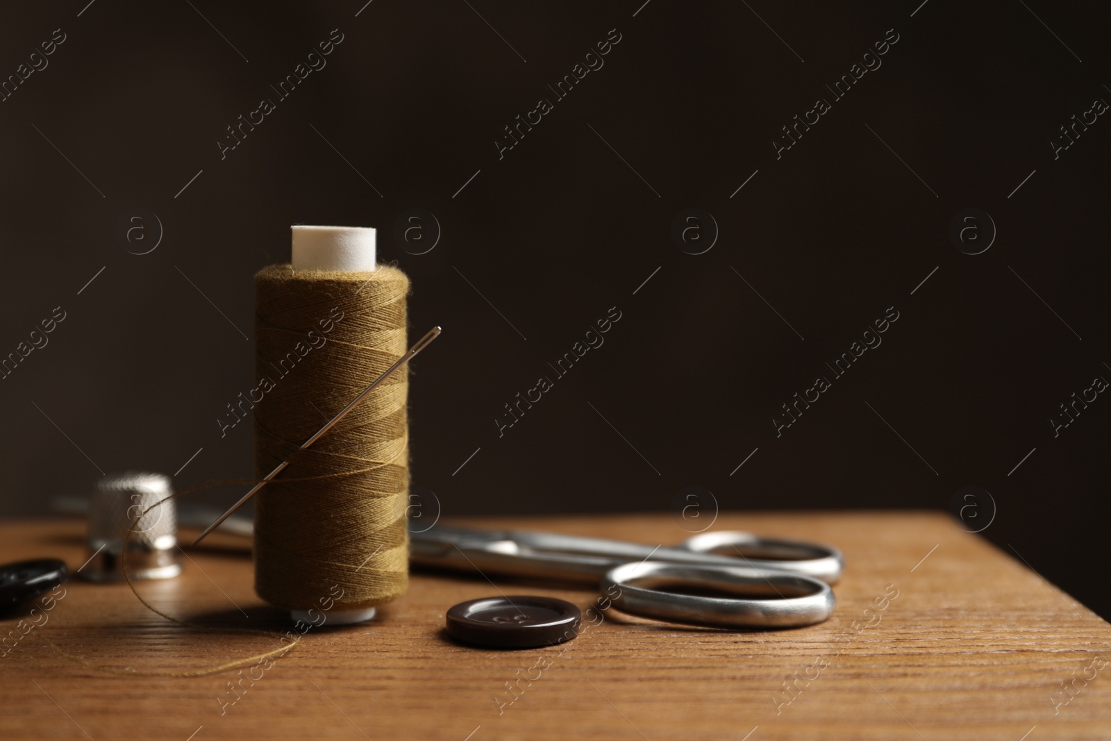 Photo of Scissors and other sewing accessories on wooden table, space for text