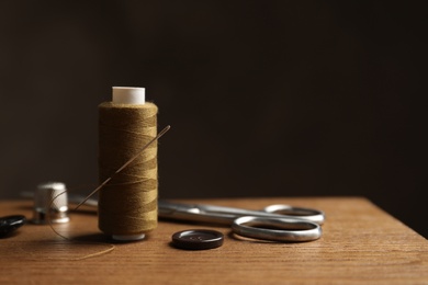 Scissors and other sewing accessories on wooden table, space for text