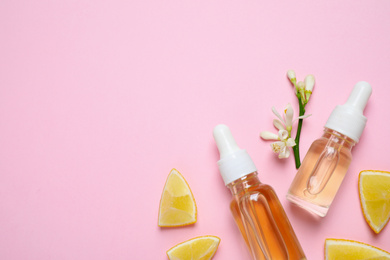 Photo of Flat lay composition with bottles of citrus essential oil on pink background. Space for text