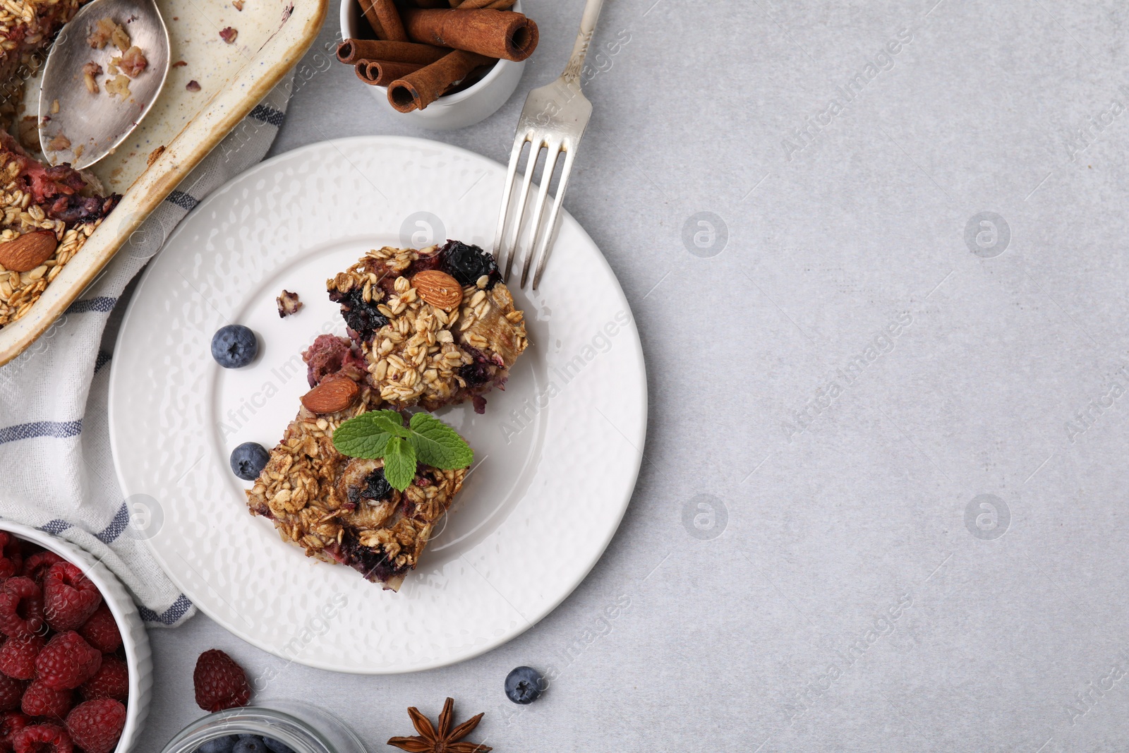 Photo of Tasty baked oatmeal with berries and almonds on light grey table, flat lay. Space for text