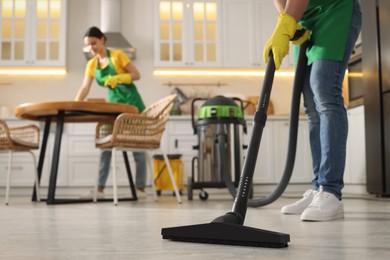 Photo of Professional janitor vacuuming floor in kitchen, closeup. Space for text