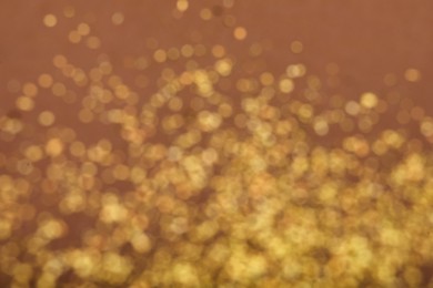 Blurred view of golden glitter on dusty rose background. Bokeh effect