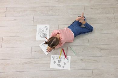 Photo of Little girl coloring on warm floor indoors, top view. Heating system