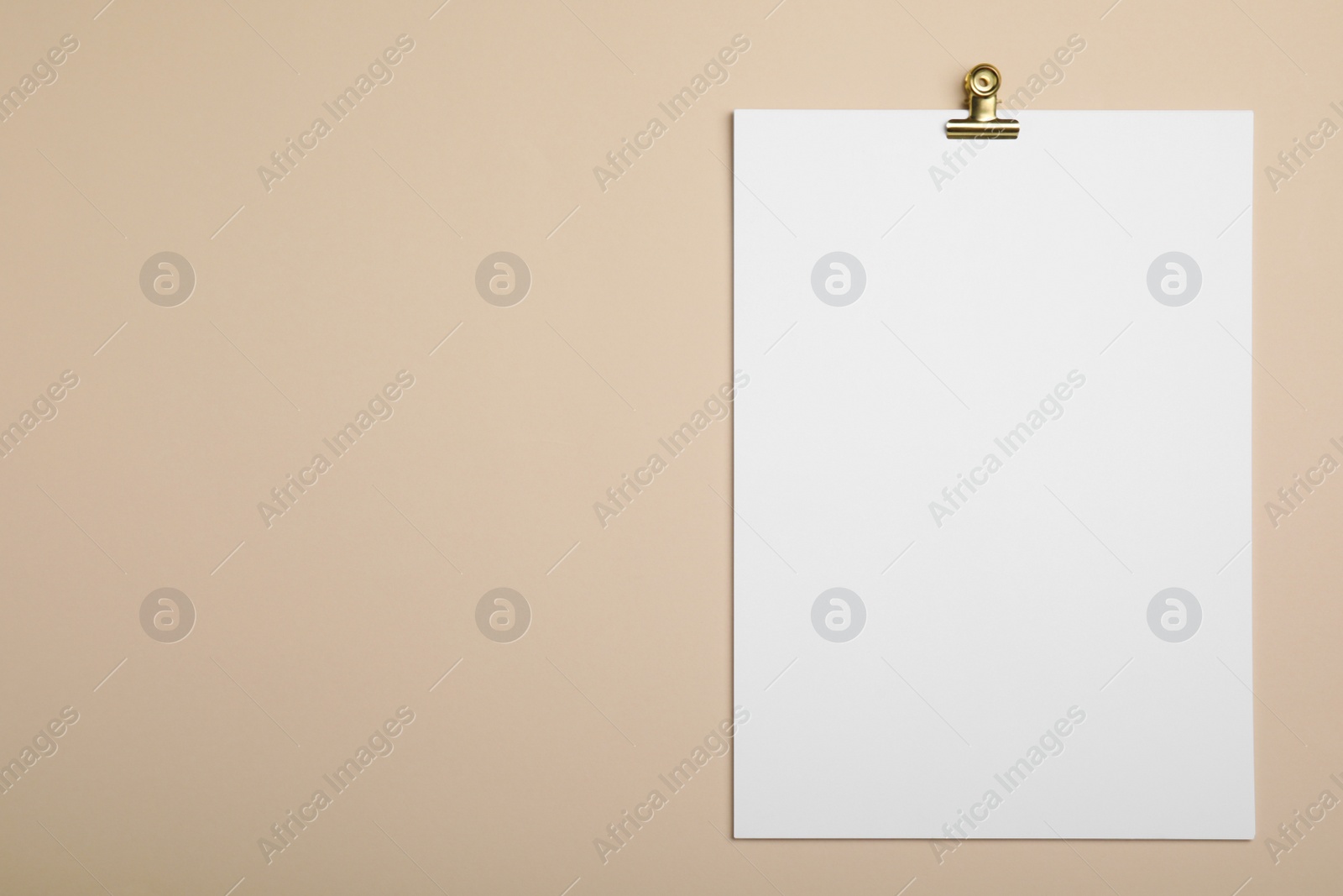 Photo of Sheet of paper with clip on beige background, top view. Space for text