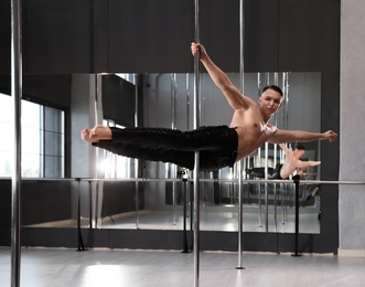 Attractive young man dancing in studio with poles