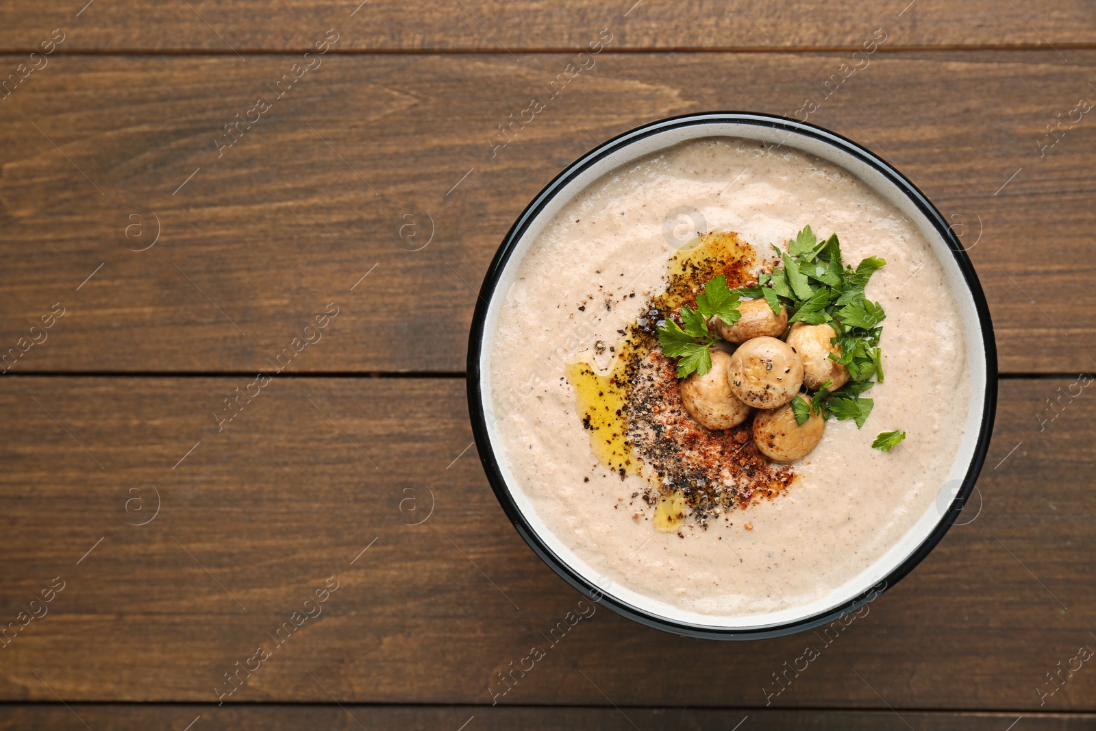 Photo of Delicious cream soup with mushrooms on wooden table, top view. Space for text