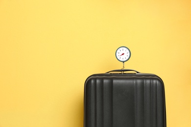 Photo of Modern suitcase and hanging scales against color background, space for text