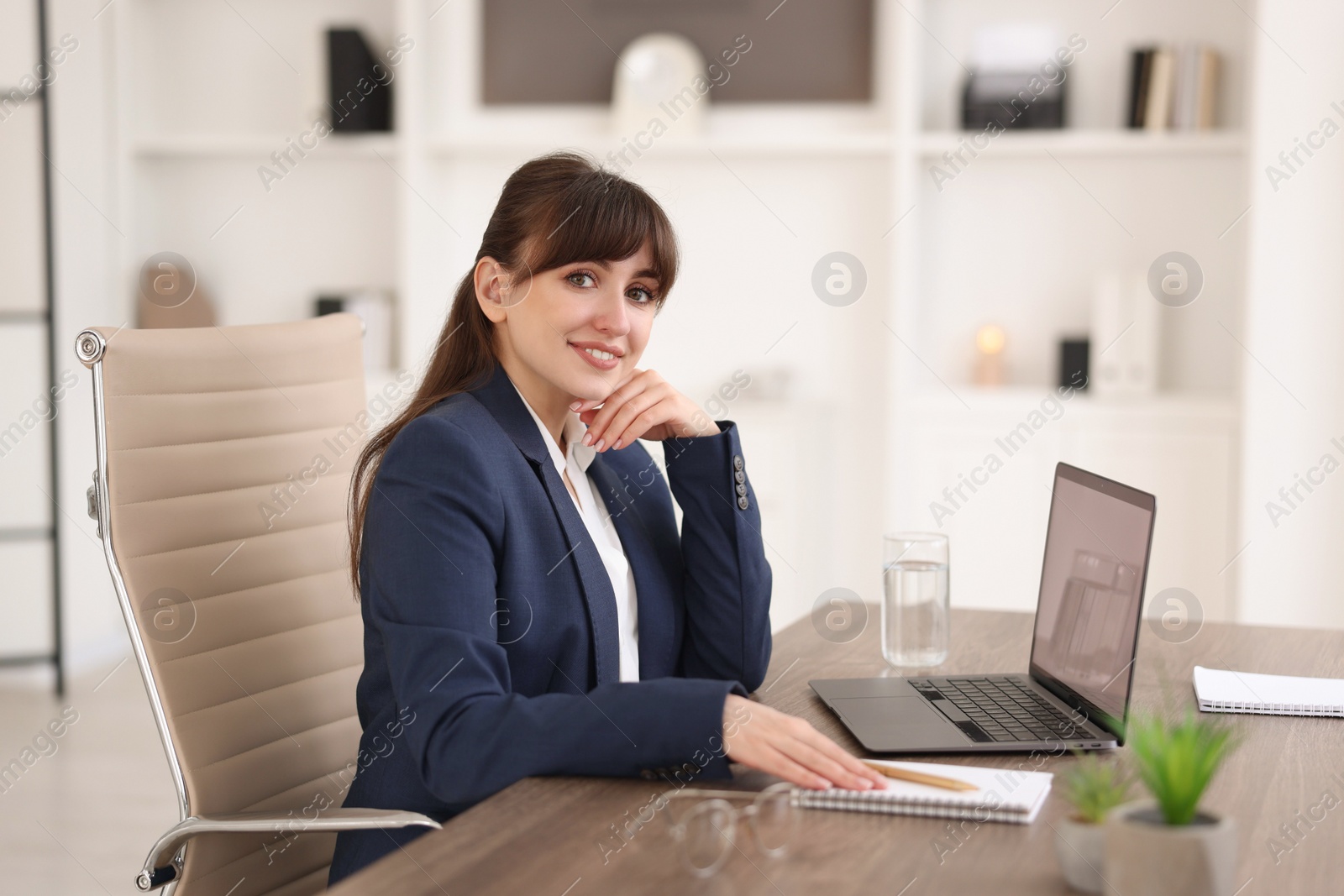 Photo of Woman watching webinar at wooden table in office