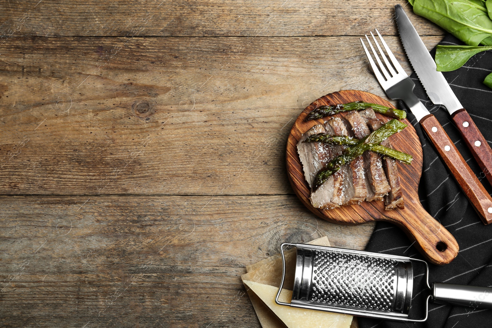 Photo of Tasty meat served with asparagus on wooden table, flat lay. Space for text